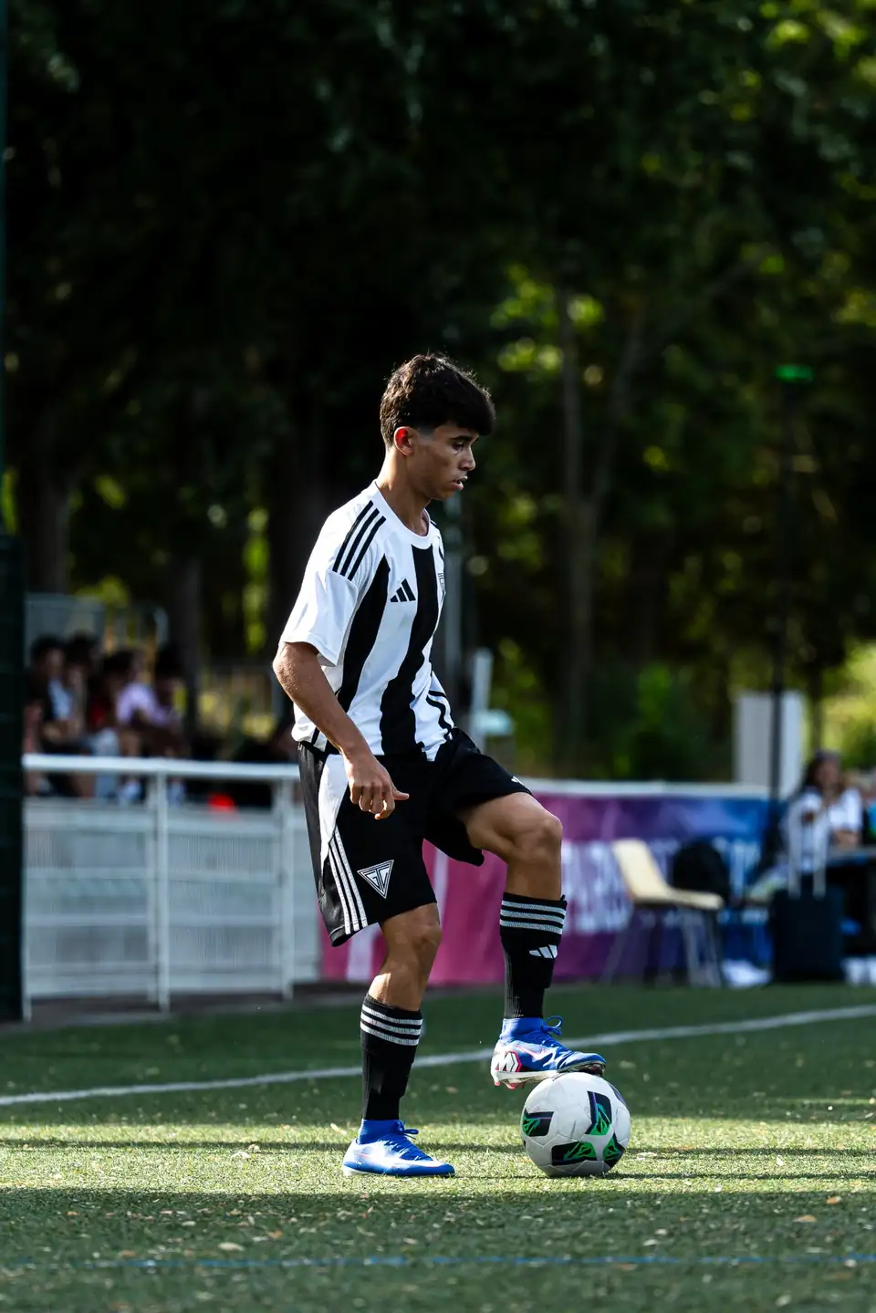 Jeune joueur en maillot rayé conduisant le ballon