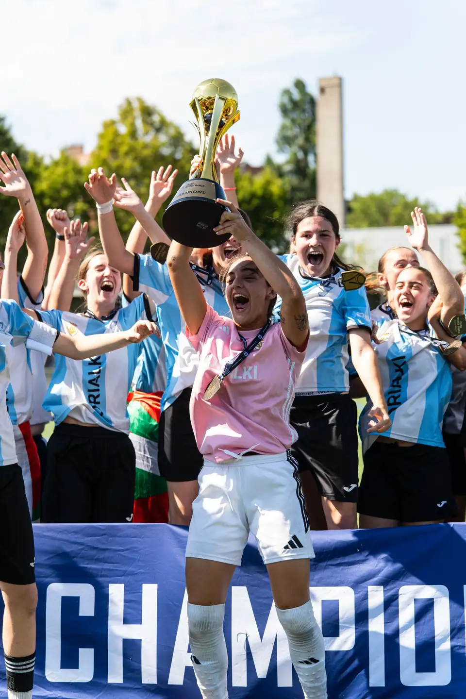 Jugadoras celebrando su título frente a la pancarta de campeonas