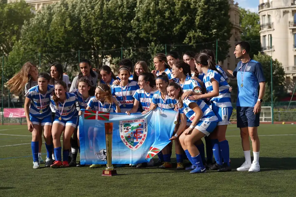 Équipe féminine posant sur le terrain avec sa bannière et son trophée