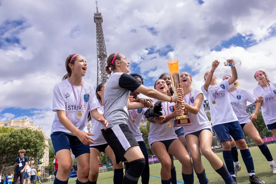 Jugadoras de fútbol celebrando su victoria con el trofeo frente a la Torre Eiffel