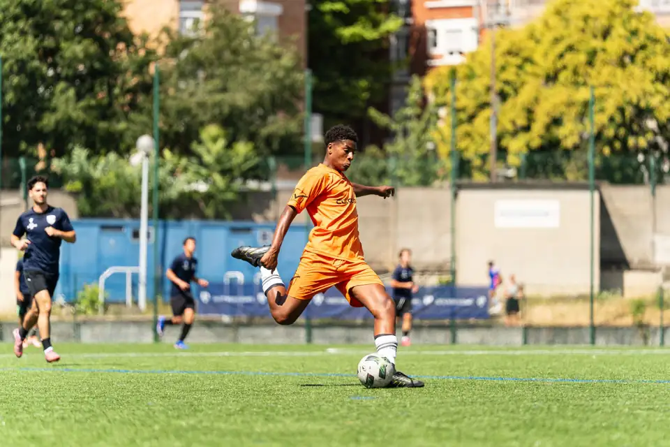 Joueur en orange frappant le ballon en pleine course