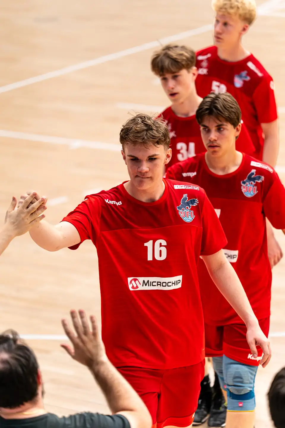 Handball players in red high-fiving